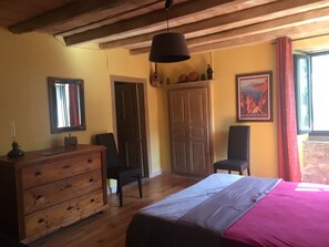 Une pièce comprenant un lit, une commode en bois, une chaise, une armoire et un tableau accroché au mur.