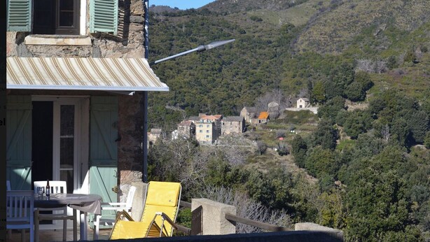 A stone building with a balcony overlooking a hillside village. - Nice village house (San Andrea di Boziu)