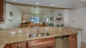 A kitchen with granite countertops, a stainless steel sink, wooden cabinets, and a dishwasher.