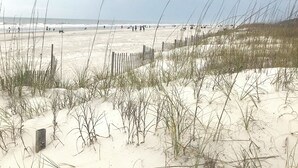 A beach with sand dunes and a wooden fence.