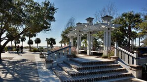 A wooden deck with steps leading to a white pergola structure.