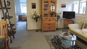 A living room with a sofa, a glass coffee table, a wooden cabinet, a television, and a rug. - 3 *** apartment in the comfort of a thatched old farmhouse from 1746 (Cuxhaven)