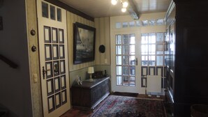 A room with a large window, a door with a grid pattern, a patterned rug, and a painting on the wall. - 3 *** apartment in the comfort of a thatched old farmhouse from 1746 (Cuxhaven)