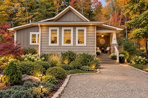 A two-story house with a front porch, a stone staircase, and a well-maintained garden.