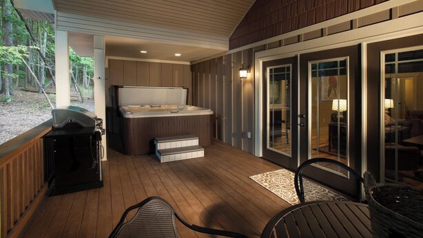 Un espace extérieur abrité comprenant un jacuzzi, une terrasse en bois et des sièges.