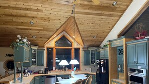 A spacious kitchen with a central island, wooden ceiling, and teal cabinetry. - big house on the private lake ,10 minutes to downtown and Lake Michigan (Traverse City)
