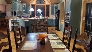 A spacious kitchen with wooden cabinets, a central island, and a dining area with a wooden table and chairs. - big house on the private lake ,10 minutes to downtown and Lake Michigan (Traverse City)