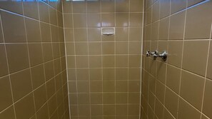 A tiled shower stall with a handheld showerhead and a soap dish.