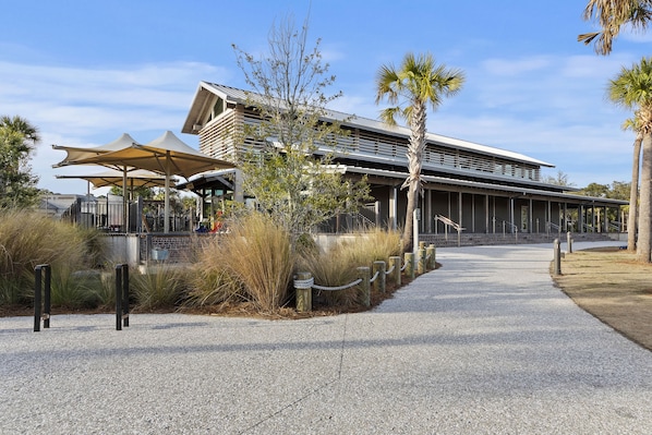 A modern building with a covered walkway, palm trees, and a gravel path.