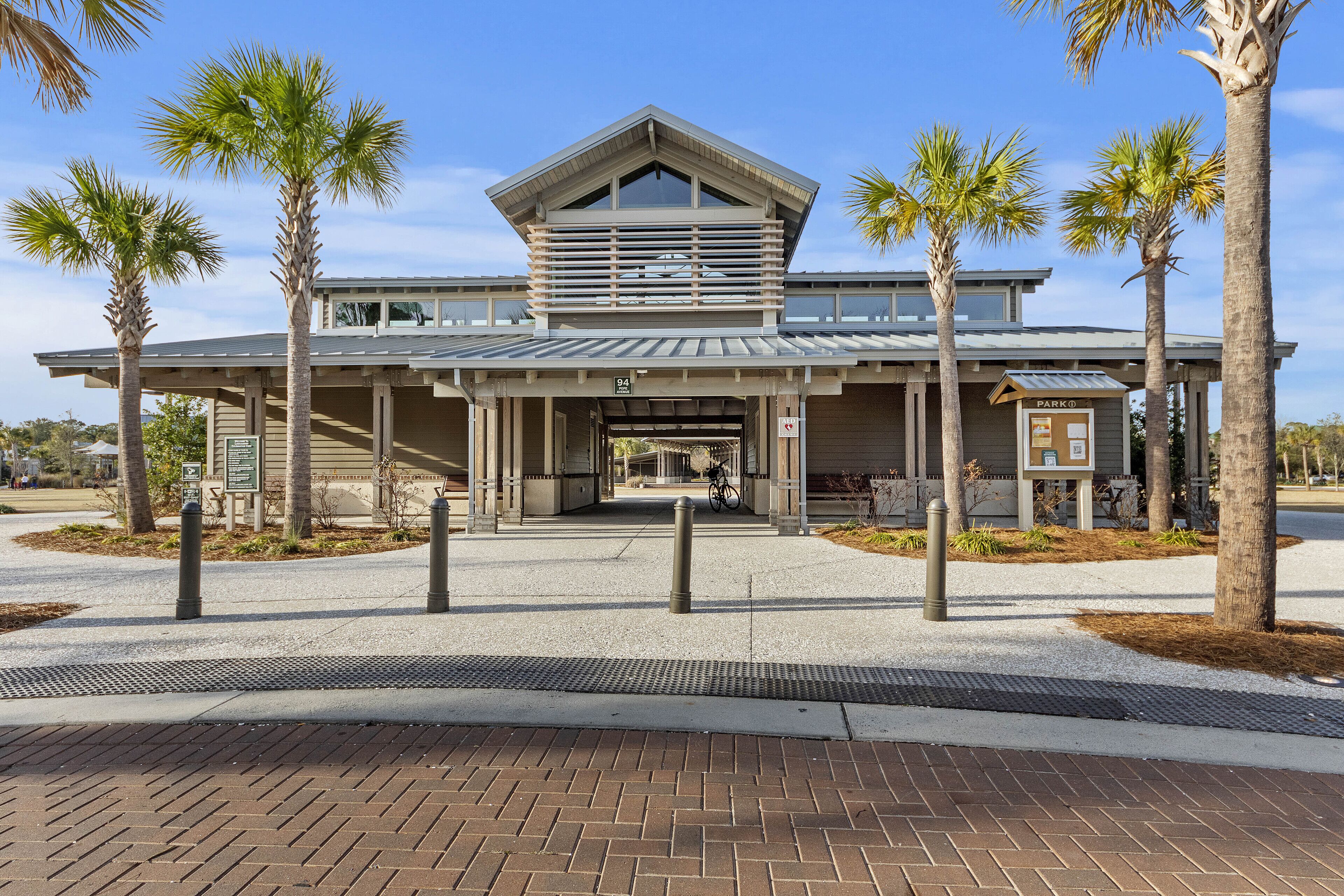A modern building with a covered entrance, palm trees, and a bike parked outside.