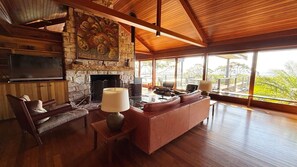 A spacious living room with a stone fireplace, leather sofas, and a large TV.