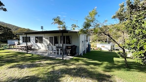 A single-story house with a patio, outdoor furniture, and a small shed. - Chriscliffs Hat Head (HAT HEAD)