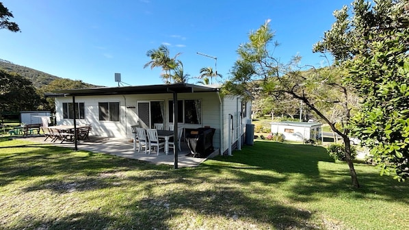 A single-story house with a patio, outdoor furniture, and a small shed.
