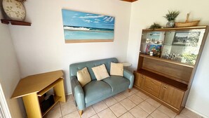 A living room with a blue sofa, a wooden cabinet with glass doors, and a painting of a beach scene.