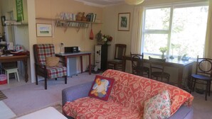 Una sala de estar acogedora con un sofá, sillas, una mesita, una estantería y una ventana con vistas.