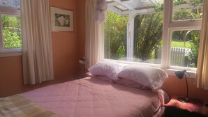 Un dormitorio con cama, ventana, un cuadro en la pared y lámpara.