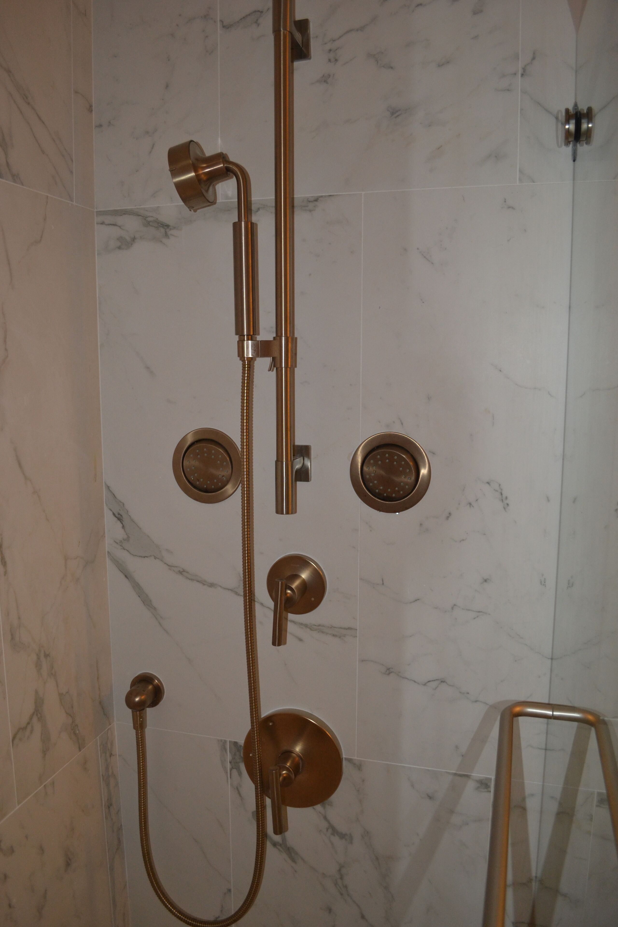 A bathroom with a shower system, including a handheld showerhead and a wall-mounted showerhead.