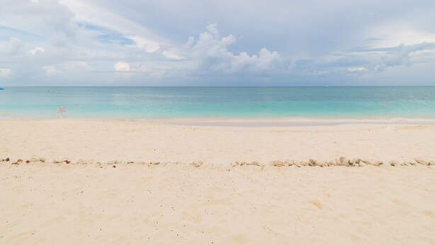 Une plage avec un ciel dégagé et une mer calme.