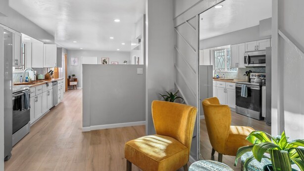 A modern kitchen with white cabinets, a wooden countertop, and a yellow chair. - Lester Place: Retro-Inspired Artist’s Escape with Pool! (Tucson)