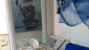 A living room with a blue sofa, a coffee table with a starfish decoration, a magazine, and a wall-mounted shelf with decorative items. - THE FISHERMAN'S HOUSE (Ospedaletti)