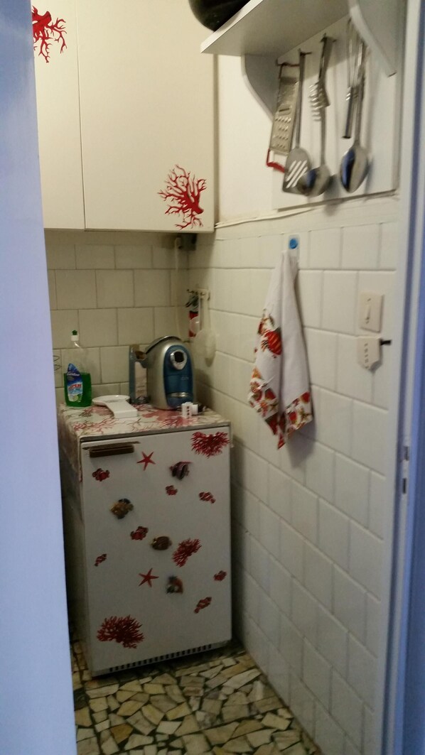 Una cucina compatta con un frigorifero, un bollitore e un lavandino.