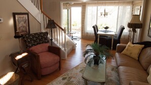A living room with a staircase, a dining area, and a view of the outdoors.