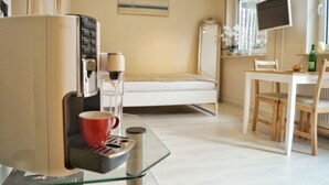 Une chambre d’hôtel de taille réduite, comprenant un lit, un petit bureau avec une chaise, une machine à café et un téléviseur.