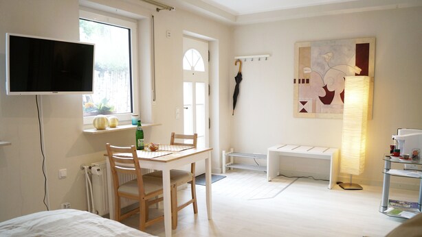 Une pièce comprenant un lit, un bureau avec une chaise, un téléviseur fixé au mur, une fenêtre donnant sur un paysage agréable et un tableau accroché au mur.