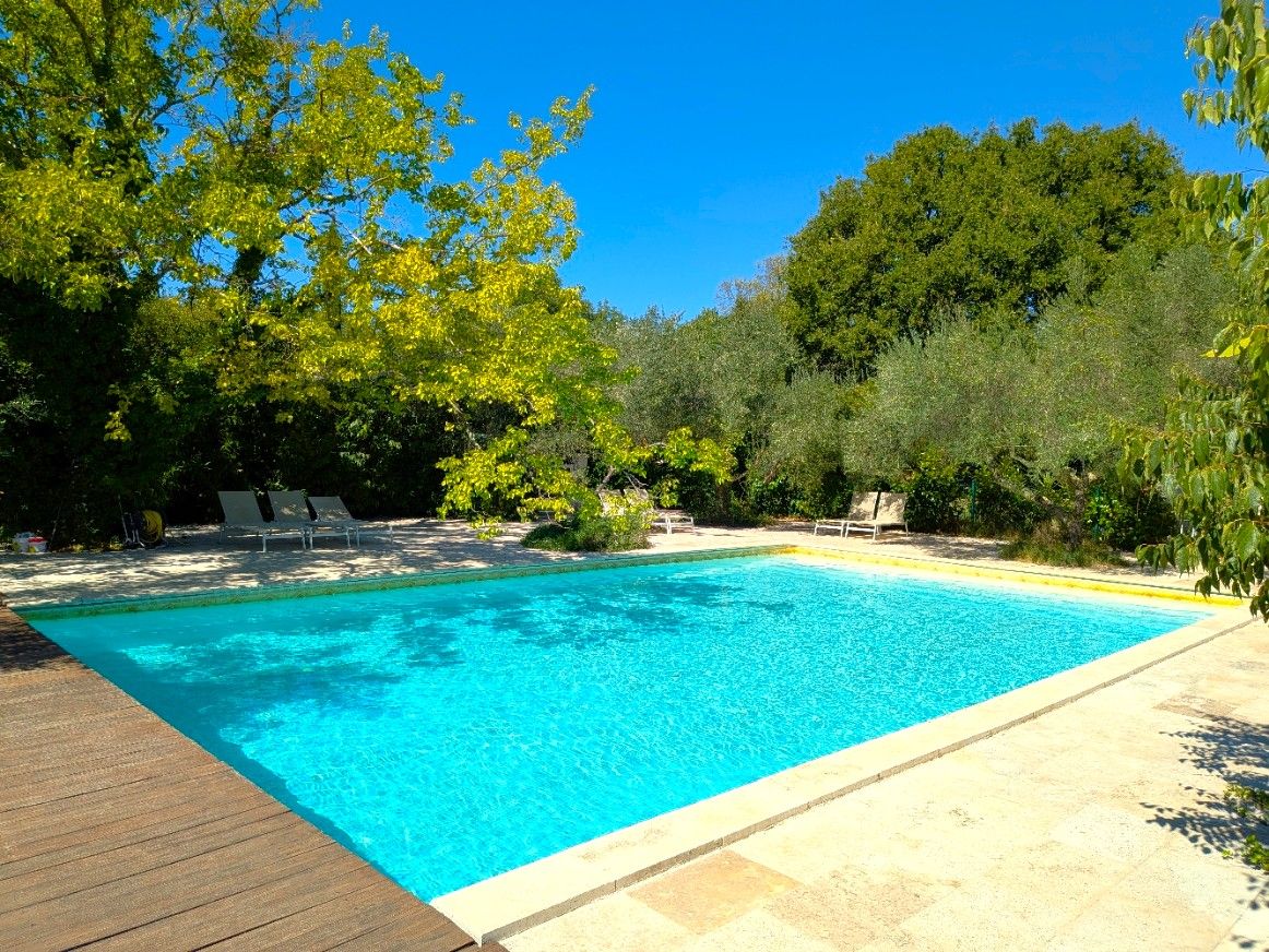 A rectangular swimming pool with a wooden deck and lounge chairs.