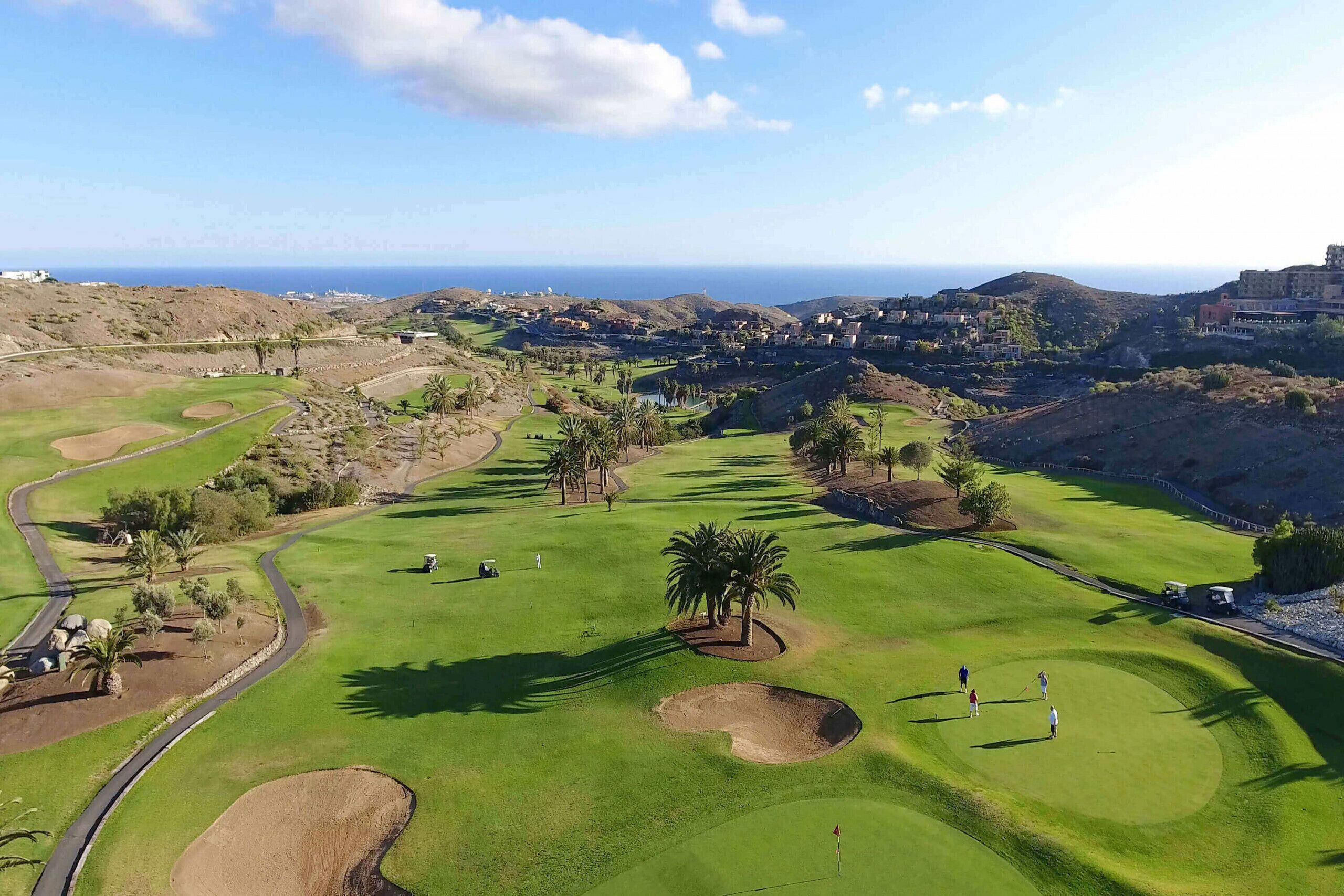 Un parcours de golf offrant une vue sur l’océan et les collines en arrière-plan.