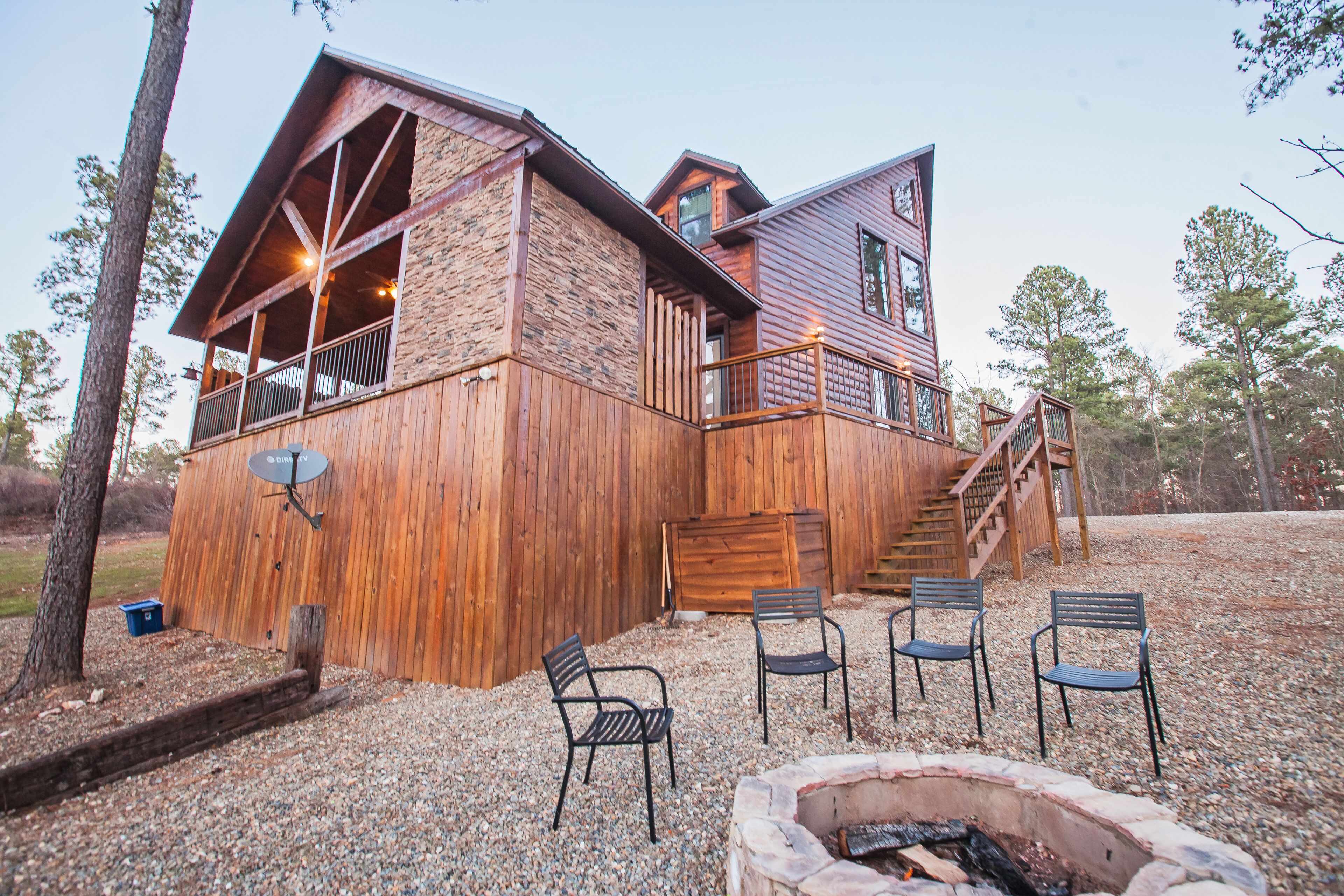 A rustic cabin with a wooden exterior, a balcony, and a fire pit area.