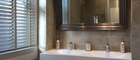 A bathroom with a large mirror, two sinks, and a shower.