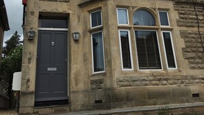A two-story building with a stone facade, multiple windows, and a dark-colored front door. - Lovely Central Bath House- w/ Parking (CG) (Bath)