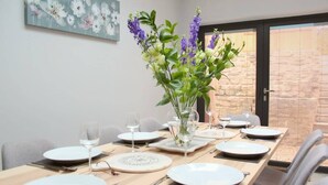 A dining table set with plates, glasses, and cutlery, with a vase of flowers in the center. - Lovely Central Bath House- w/ Parking (CG) (Bath)