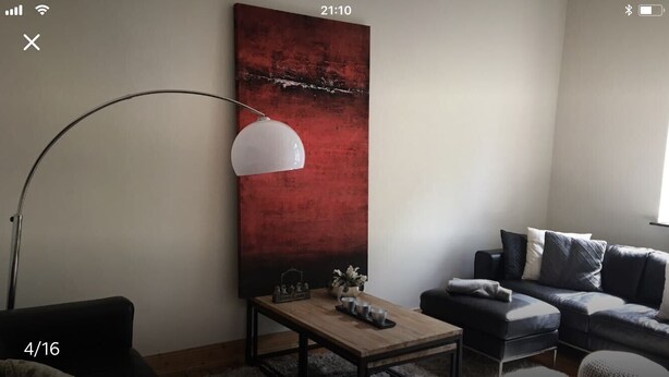 A modern living room with a large abstract painting, a floor lamp, a sofa, and a coffee table.