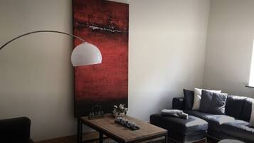 Ein modernes Wohnzimmer mit einem großen abstrakten Gemälde, einer Stehlampe, einem Sofa und einem Couchtisch.