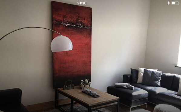 A modern living room with a large abstract painting, a floor lamp, a sofa, and a coffee table.