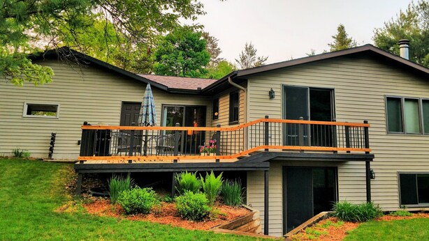 A two-story house with a balcony, a covered patio, and a front yard with plants. - The Sixth Green at Lake Arrowhead by Sand Valley Golf Resort (Nekoosa)