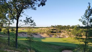 A golf course with sand bunkers, trees, and a clear sky. - The Sixth Green at Lake Arrowhead by Sand Valley Golf Resort (Nekoosa)