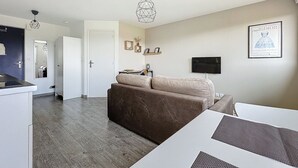 Un salon moderne avec un canapé marron, une table basse blanche et un téléviseur fixé au mur.