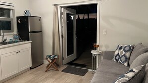 A compact living space with a kitchenette, a sofa with patterned cushions, and a small table with glasses. - 1 Bedroom Suite in a duplex house- private heated pool for you- walk to beach  (Lauderdale-By-The-Sea)
