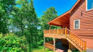 A log cabin with a wooden deck and a covered porch.