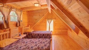 A cozy attic bedroom with wooden walls and a sloped ceiling.