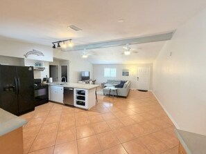 A spacious kitchen with a central island, a dining area with a sofa, and a living room with a couch.