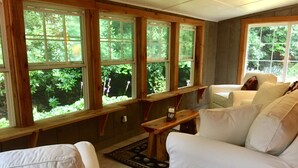 A room with a large window, a white sofa, and a wooden bench.