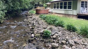 A house with a hot tub, a deck, and a river.