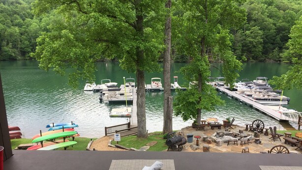 A lakeside view with docked boats, picnic tables, and a barbecue area.