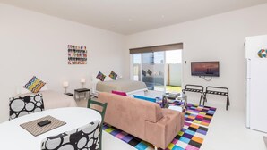 A modern living room with a sofa, a dining table, and a TV.