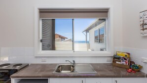 A kitchen with a large window, a sink, and a stove.