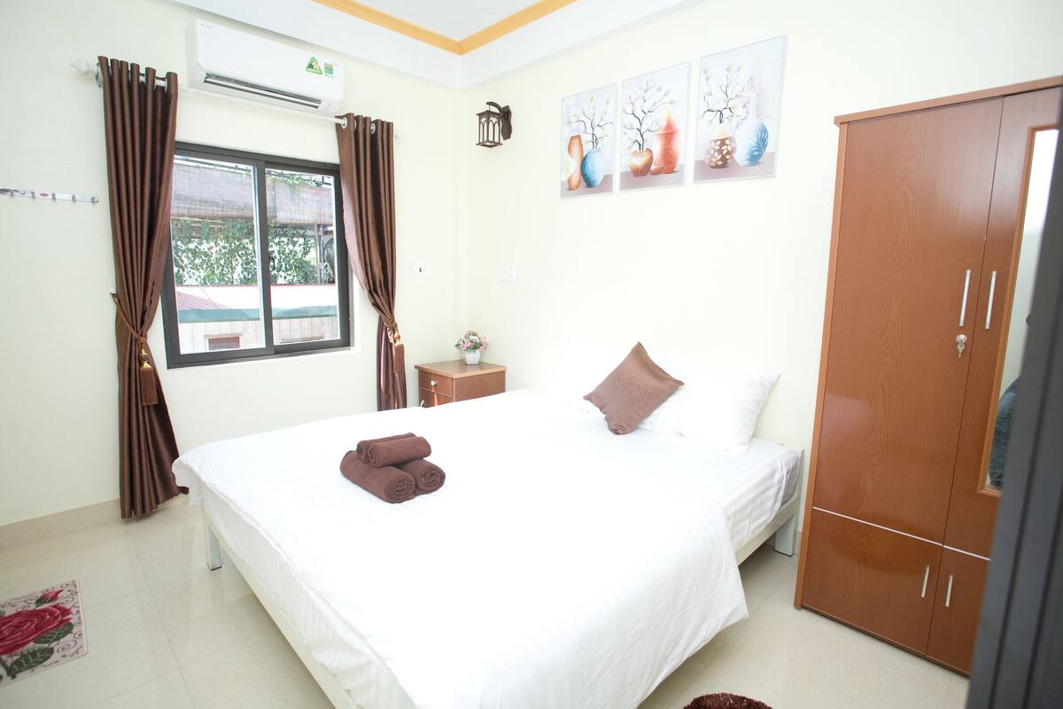A neatly arranged bedroom with a bed, a wardrobe, and a bedside table.